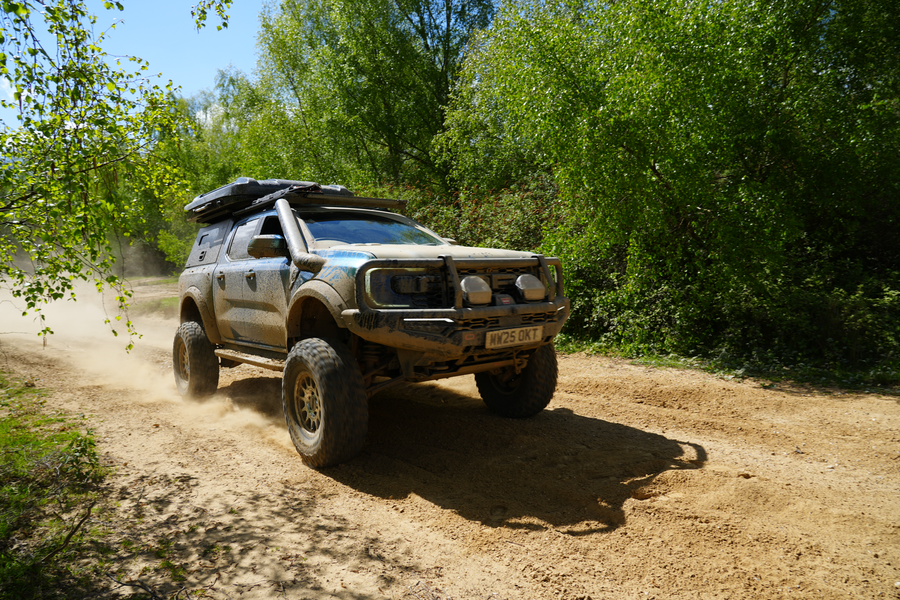 Modified Ford Ranger Raptor driving a dusty trail with roof tent, snorkel and bull bar