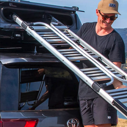 Man removing ladder form roof tent on a car with a clear sky background
