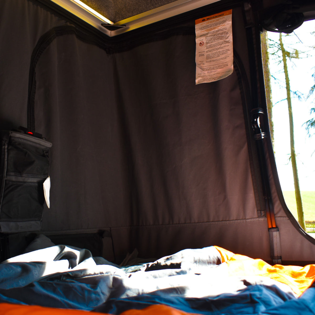 Close-up of a tent interior with a curtain and visible outdoors.
