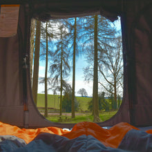 View from inside a tent looking out onto trees and a field